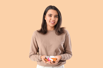 Young woman with different means of contraception on beige background