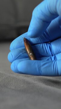 A forensic scientist wearing latex gloves holds a bullet in his hand at a crime scene.
Murder scene and a police officer holding evidence.
Forensic scientist work and murder investigation.
Crime polic