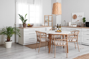 Interior of beautiful kitchen with white counters, dining table, chairs and lamp