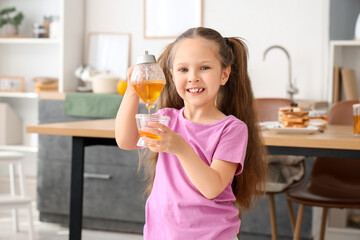 Cute little girl with honey in kitchen
