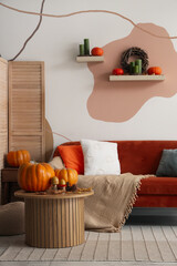 Interior of cozy living room with sofa, table and autumn decor