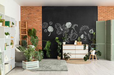Stylish interior of living room with tropical plants and chalk drawing on black wall
