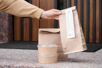 Hand of woman with delivered order on porch