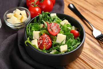 Composition with bowl of healthy arugula salad and ingredients on wooden background, closeup