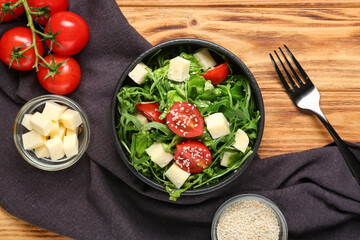 Composition with bowl of healthy arugula salad and ingredients on wooden background, closeup