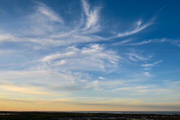 Sunset sky background over the coast of Hudson Bay, blue sky with hints of yellow and orange, and white wispy clouds
