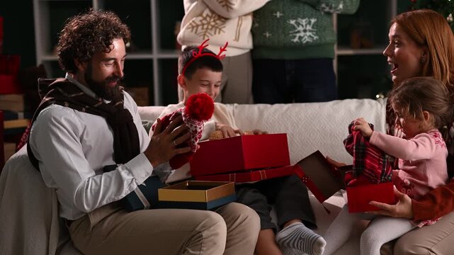 Family opening christmas presents on sofa