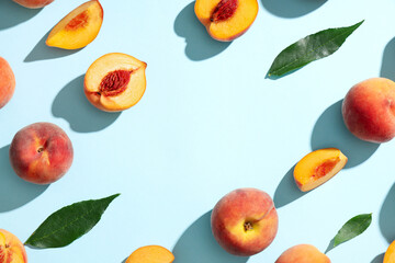 Frame made of sweet ripe peaches and leaves on blue background