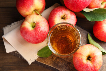 Delicious cider in glass, apples and leaves on wooden table, flat lay