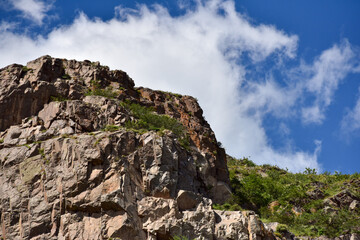 Rugged Rocky Cliff Against a Blue Sky with Scattered Clouds