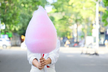Beautiful young woman with cotton candy in park, outdoors