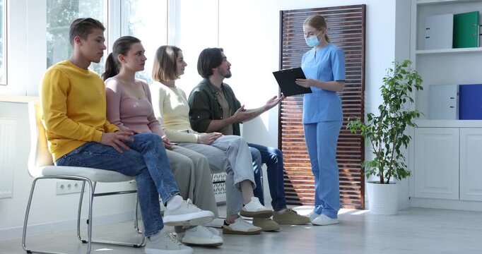 People waiting in queue on chairs at hospital