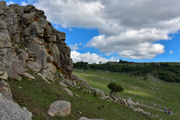 Rocky Cliff Overlooking a Lush Green Valley Under a Cloudy Sky