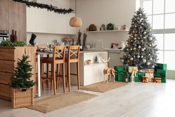 Interior of light kitchen with Christmas trees, counters and dining table