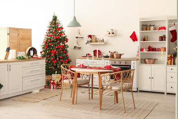 Interior of light kitchen with Christmas tree, dining table and counters