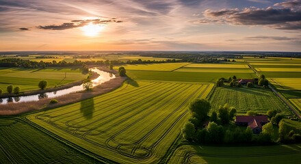 Aerial view of rural landscape at sunset with river crossing green and yellow fields