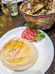 Traditional hummus topped with olive oil, served with a basket of fresh bread on a table at a local restaurant in Riyadh, Saudi Arabia