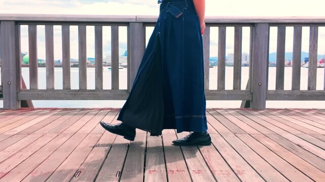 女性が港町のウッドデッキを歩く様子