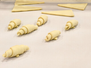 Creative pastry preparation transforms dough into charming miniature croissants in a cozy kitchen setting