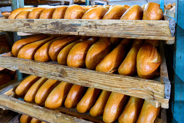 Freshly baked bread rolls rest in wooden trays after coming out of the oven, showcasing their golden crusts and soft interiors