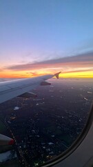 Airplane wing at sunset over city