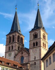 Fototapeta premium Two tall, pointed church spires, dark roofs, light stone, clock faces