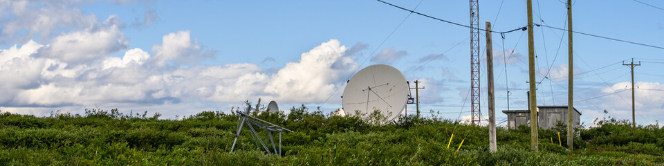 Technology and communication in remote areas, satellite dish, communication towers with yagi antennas, power lines and phone lines, consolidated out in the remote bush
