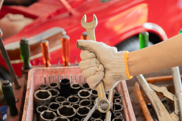 Small business garage mechanics in small business garage grips tools with safety glove, close-up wrench fix  preparation, workshop focus, professional readiness in automotive repair work by technician