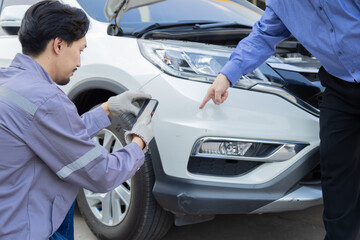 Mechanic taking photo of car damage while customer points at scratch, automotive inspection process...