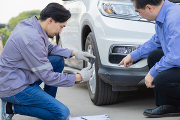 Mechanic taking photo of car damage while customer points at scratch, automotive inspection process for insurance claim or repair documentation, professional service detail in workshop scene