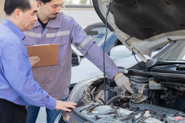 Mechanic taking photo of car damage while customer points at scratch, automotive inspection process...