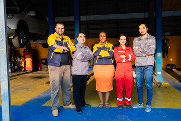 Obraz premium Group of diverse mechanics standing together in workshop showing thumbs up, teamwork in garage small business, partnership and multicultural collaboration reflecting trust in automotive industry