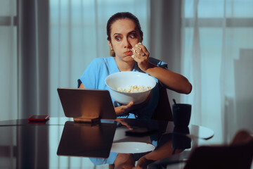 Woman Eating Popcorn Watching a Show on her Tablet. Carefree lady watching a suspenseful true crime...