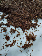Close-up of dried tea leaves scattered on a white surface. Natural texture background of herbal or black tea, commonly used for brewing beverages and culinary ingredients.