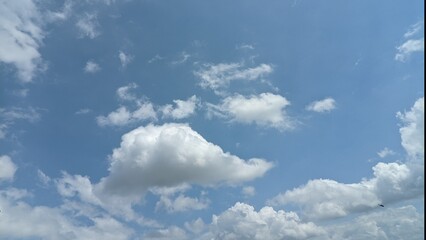 A dynamic blue sky filled with large, fluffy white clouds with a visually engaging natural backdrop.