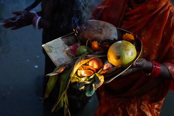hindu devotee performing holy rituals with daali offerings at chhath puja celebration