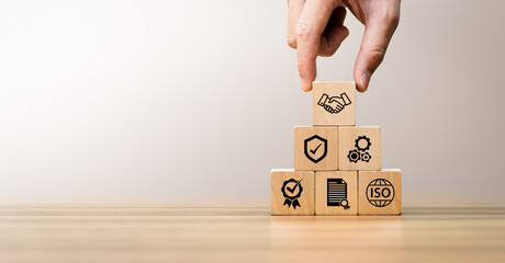 Hand stacking wooden blocks with quality, certification, and ISO icons, symbolizing business...