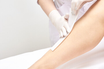 Female receiving leg waxing treatment by professional in spa setting for smooth skin care.