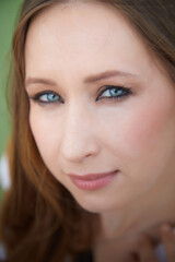 Fototapeta premium Close-up portrait of a woman with striking blue eyes in a natural outdoor setting during daytime