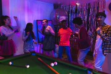 Teenagers dancing and celebrating at home party with disco ball and decorations