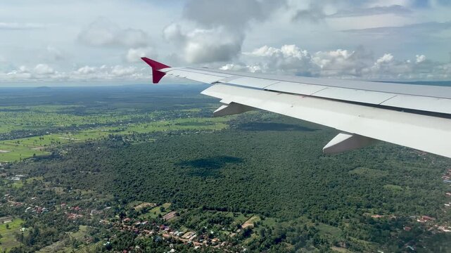 Aircraft wing over the green fields and cloudy sky