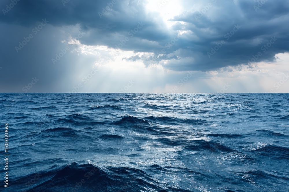 Poster sunbeams shining through dark clouds illuminate a vast blue ocean, creating a stunning contrast betw