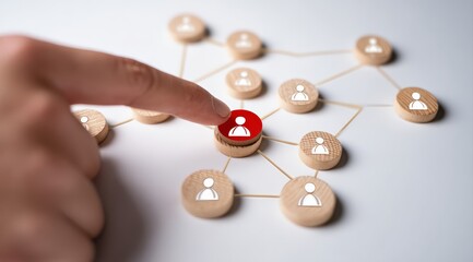 Hand is choosing a red person icon among many white ones in a network of wooden pawns connected by strings, representing human resources management