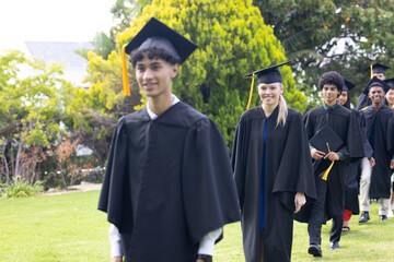 Graduating students walking outdoors in caps and gowns, smiling and celebrating