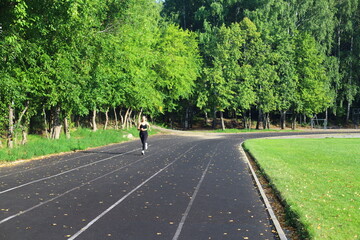 Athletic woman trains on outdoor stadium in summer day. Fitness workout.