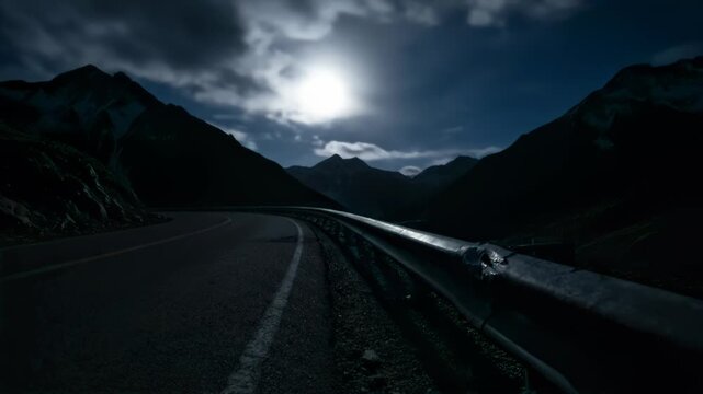 Isolated mountain hairpin road with headlights and clouds