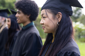 Graduating students in caps and gowns smiling outdoors, celebrating achievement