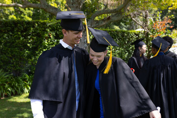 Graduating students in caps and gowns celebrating joyfully outdoors together