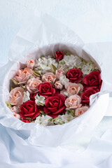 Fototapeta premium Beautiful arrangement of marshmallow flowers in a white round box, featuring vibrant red, soft pink, and delicate white blooms, showcasing unique floristry concept with copy space