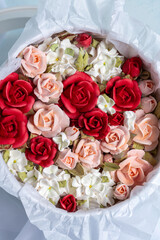 Beautiful arrangement of marshmallow flowers in a white round box, featuring vibrant red, soft pink, and delicate white blooms, showcasing unique floristry concept with copy space